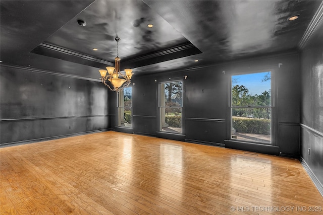 unfurnished room with crown molding, light hardwood / wood-style floors, a tray ceiling, and an inviting chandelier