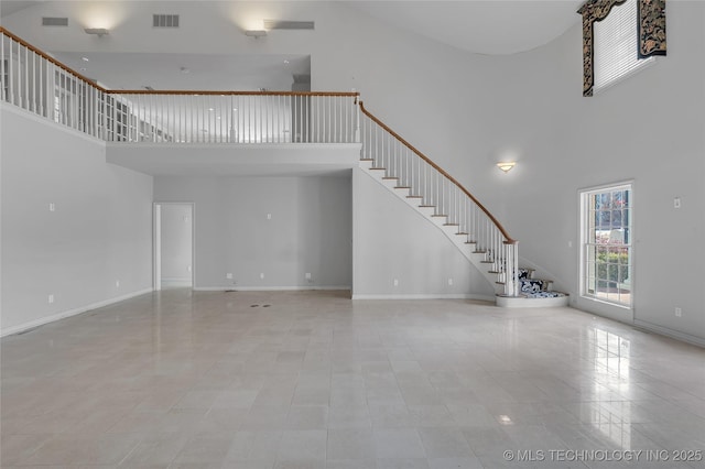 unfurnished living room with a towering ceiling and light tile patterned floors