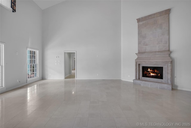 unfurnished living room with a tile fireplace and a towering ceiling