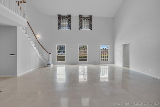 unfurnished living room featuring a towering ceiling