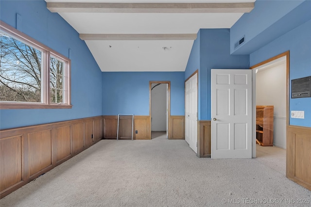 interior space with light colored carpet and lofted ceiling with beams