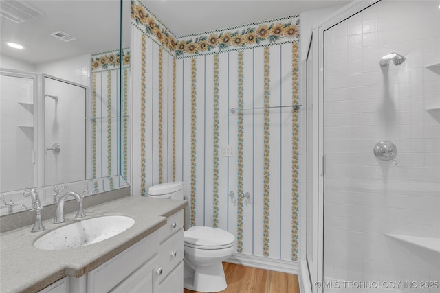 bathroom featuring hardwood / wood-style flooring, toilet, an enclosed shower, and vanity