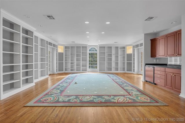 unfurnished living room with built in features and light wood-type flooring