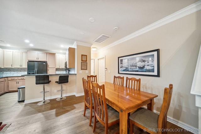 dining space featuring light hardwood / wood-style floors and ornamental molding