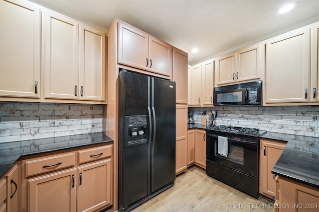 kitchen featuring black appliances, dark stone countertops, light wood-type flooring, and tasteful backsplash