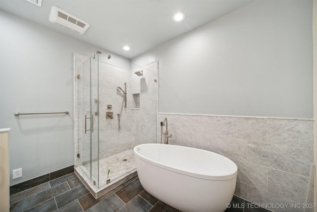 bathroom featuring plus walk in shower and tile walls