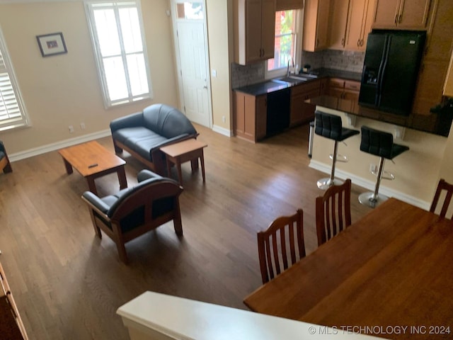 kitchen with backsplash, light hardwood / wood-style flooring, black appliances, and a healthy amount of sunlight