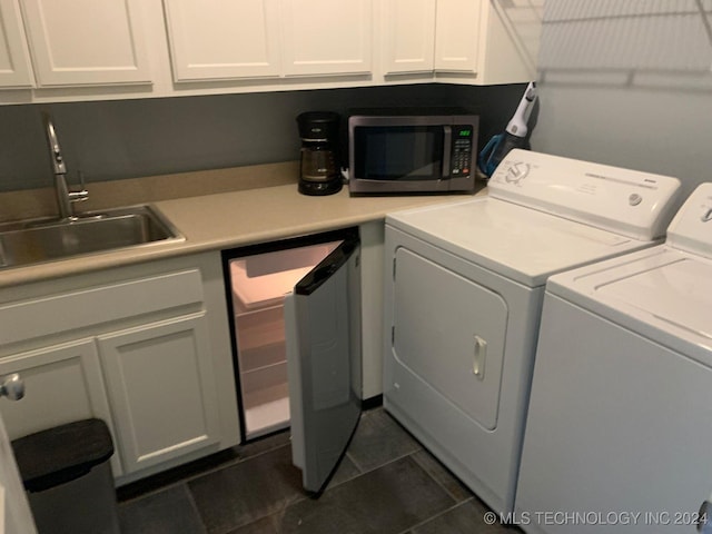 clothes washing area with washer and dryer, dark tile patterned flooring, cabinets, and sink