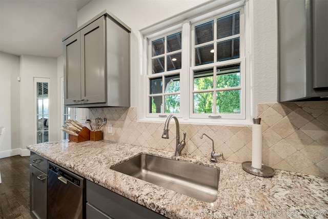 kitchen with gray cabinetry, sink, dark wood-type flooring, stainless steel dishwasher, and decorative backsplash