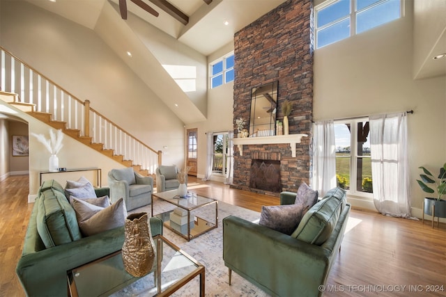 living room with a fireplace, light hardwood / wood-style flooring, and a high ceiling