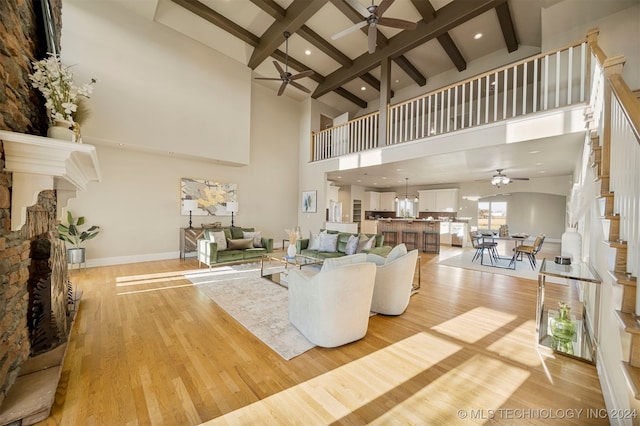 living room featuring a fireplace, light hardwood / wood-style floors, high vaulted ceiling, and beamed ceiling