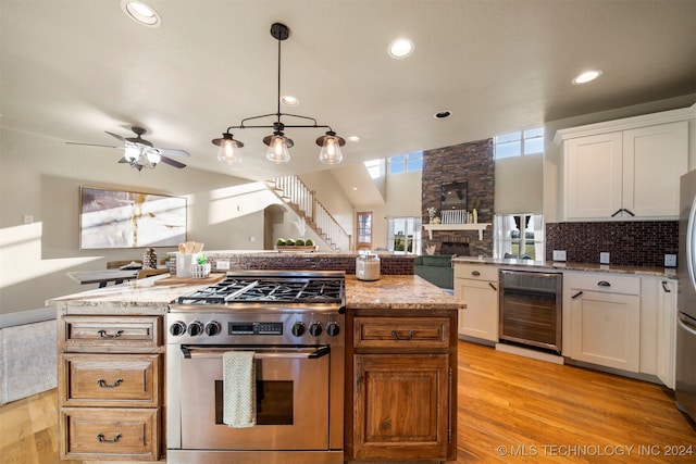 kitchen featuring light stone countertops, wine cooler, stainless steel stove, and white cabinetry