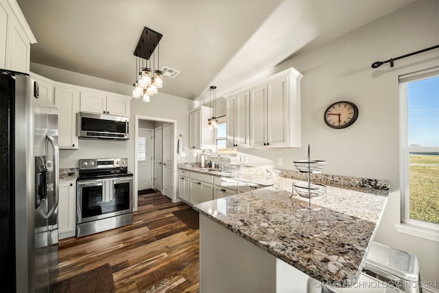 kitchen featuring kitchen peninsula, stainless steel appliances, vaulted ceiling, pendant lighting, and white cabinets