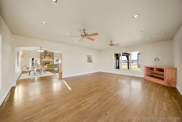 unfurnished living room with ceiling fan, a fireplace, and light hardwood / wood-style flooring