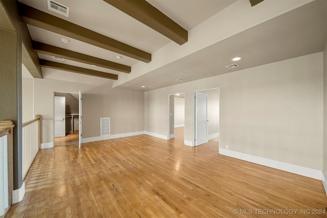 unfurnished living room featuring beamed ceiling and light hardwood / wood-style flooring