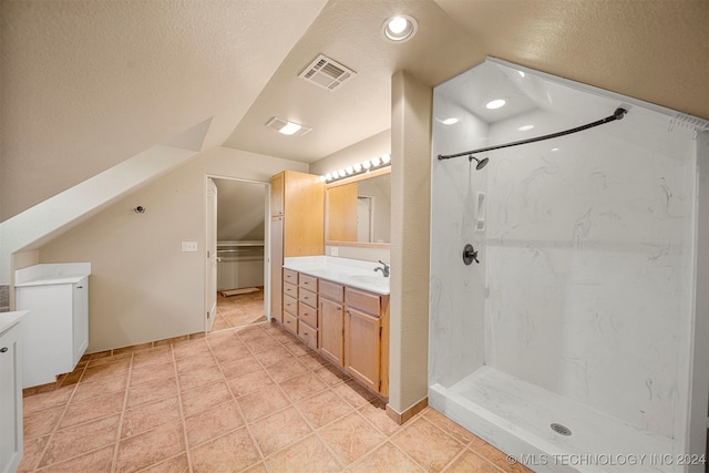 bathroom with vanity, a textured ceiling, a shower, tile patterned flooring, and lofted ceiling