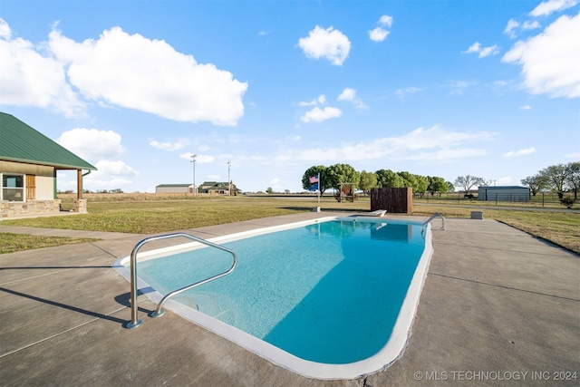 view of swimming pool featuring a lawn, a diving board, and a patio area