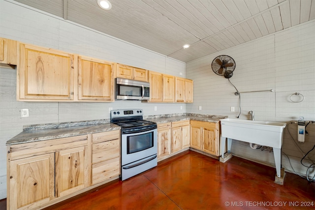 kitchen with stainless steel appliances, light brown cabinetry, and tile walls