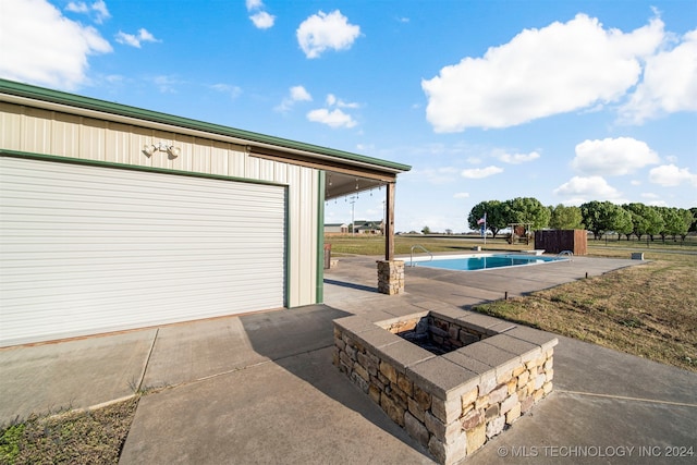 view of patio / terrace featuring a garage and an outdoor fire pit