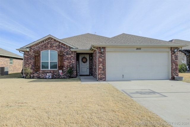 single story home with central air condition unit and a garage