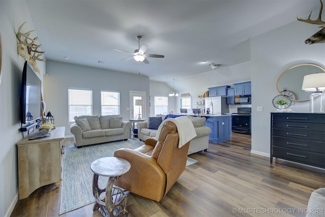 living room with ceiling fan with notable chandelier and hardwood / wood-style flooring