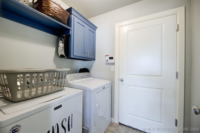 laundry room with washing machine and dryer, light tile patterned floors, and cabinets