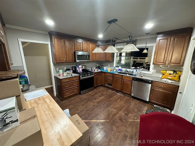 kitchen with sink, dark hardwood / wood-style flooring, crown molding, pendant lighting, and appliances with stainless steel finishes