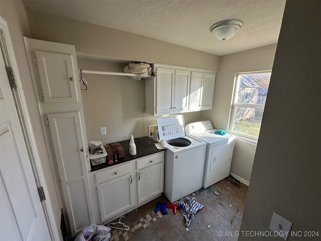 washroom with cabinets, a textured ceiling, light tile patterned flooring, and washing machine and clothes dryer