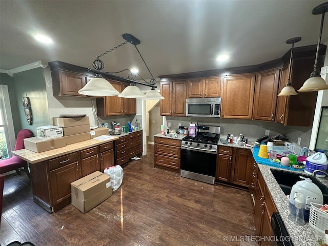 kitchen featuring dark hardwood / wood-style flooring, light stone counters, ornamental molding, stainless steel appliances, and pendant lighting