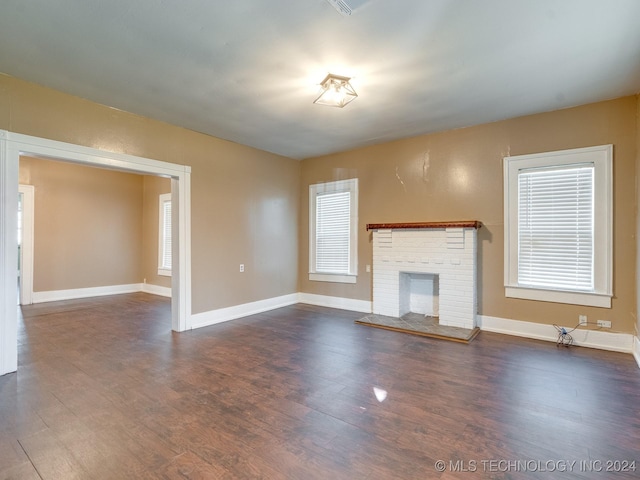 unfurnished living room with a fireplace, dark hardwood / wood-style flooring, and plenty of natural light