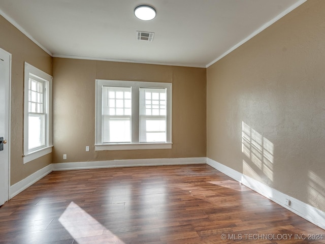 empty room featuring plenty of natural light, dark hardwood / wood-style flooring, and crown molding