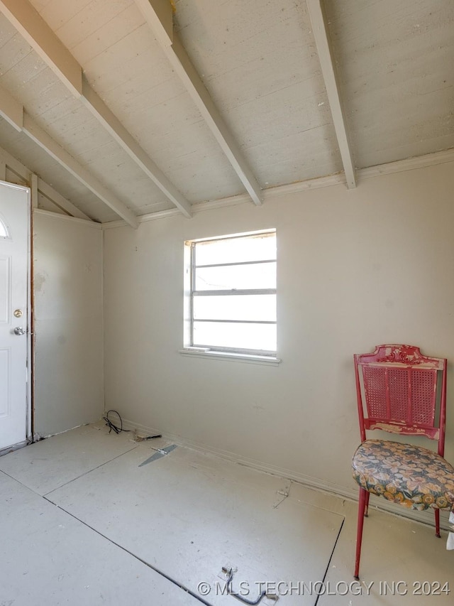 unfurnished room with lofted ceiling with beams