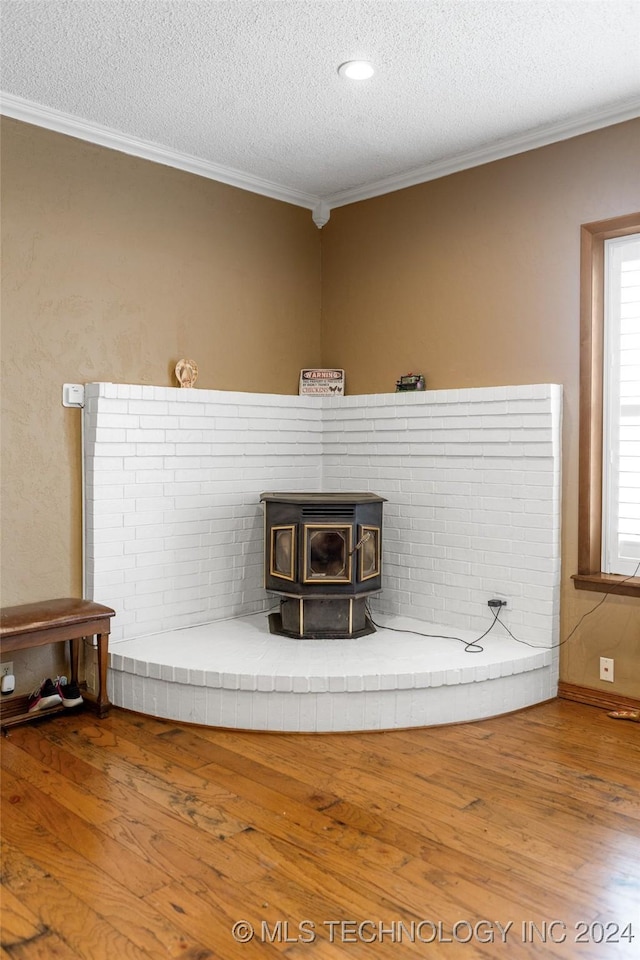 room details with crown molding, wood-type flooring, a textured ceiling, and a wood stove