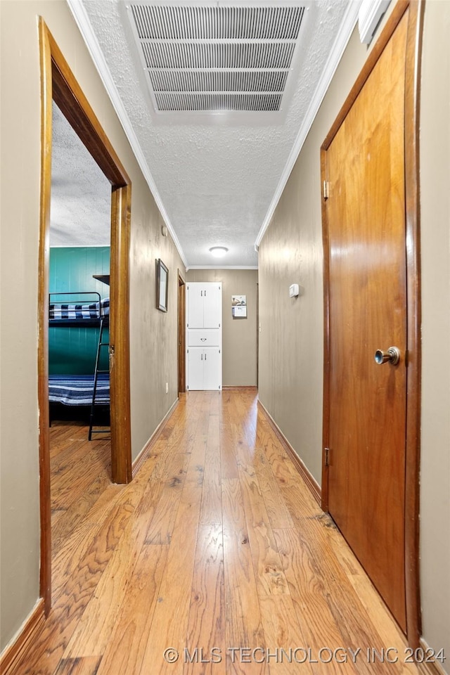 hall featuring crown molding, a textured ceiling, and light hardwood / wood-style floors