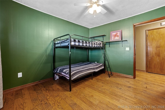 bedroom with light wood-type flooring, ceiling fan, and wood walls