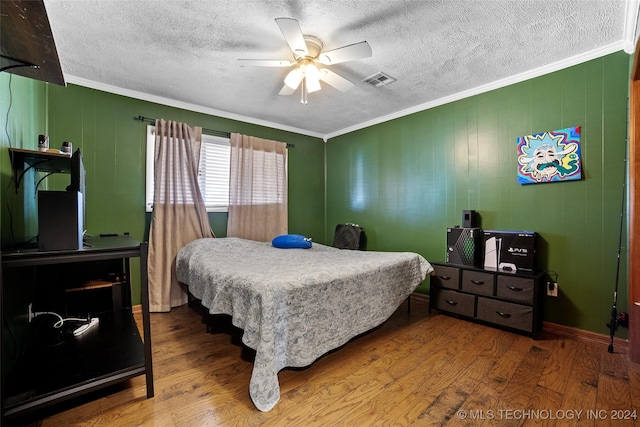 bedroom with hardwood / wood-style flooring, crown molding, wooden walls, and ceiling fan