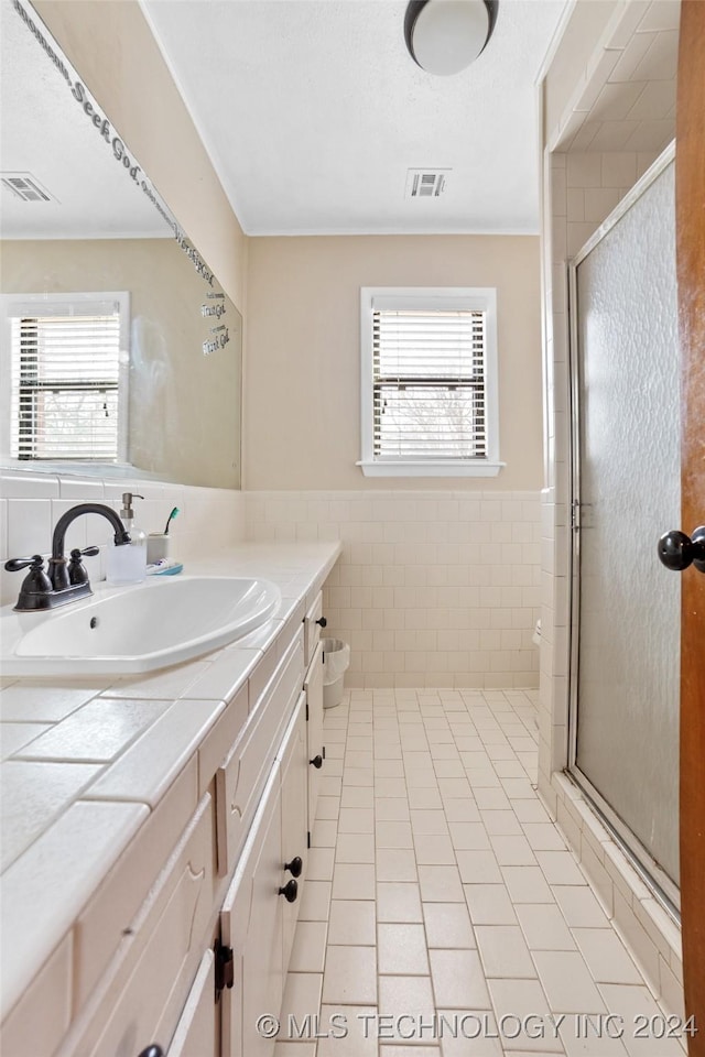 bathroom with tile patterned flooring, tile walls, vanity, an enclosed shower, and toilet