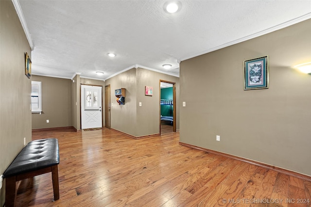 interior space featuring ornamental molding, a textured ceiling, and light wood-type flooring