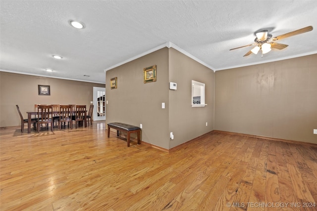 living room with crown molding, ceiling fan, a textured ceiling, and light wood-type flooring