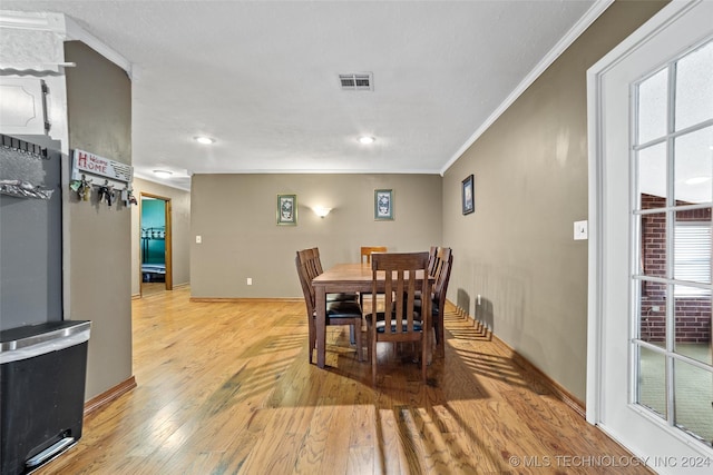 dining space with ornamental molding and light wood-type flooring