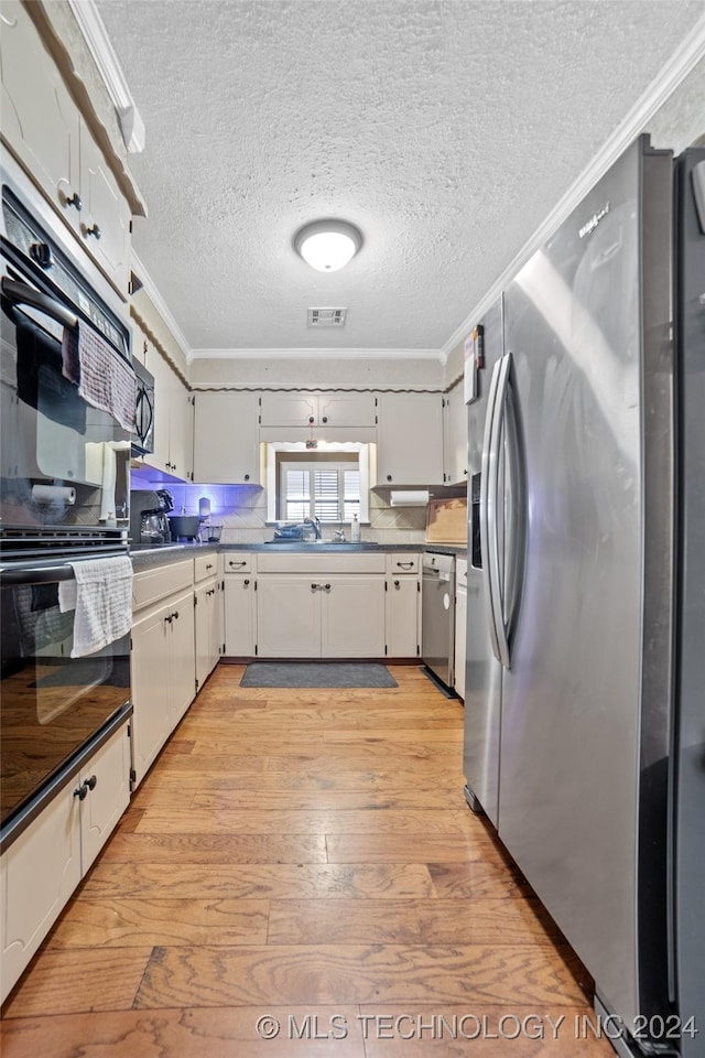 kitchen with stainless steel appliances, crown molding, a textured ceiling, and light hardwood / wood-style flooring