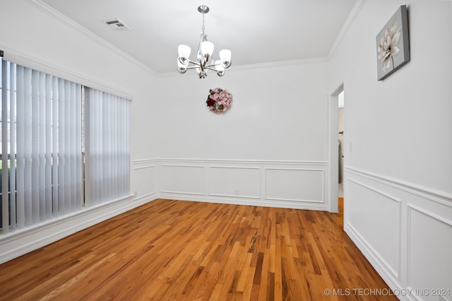 spare room featuring hardwood / wood-style flooring, crown molding, and a notable chandelier