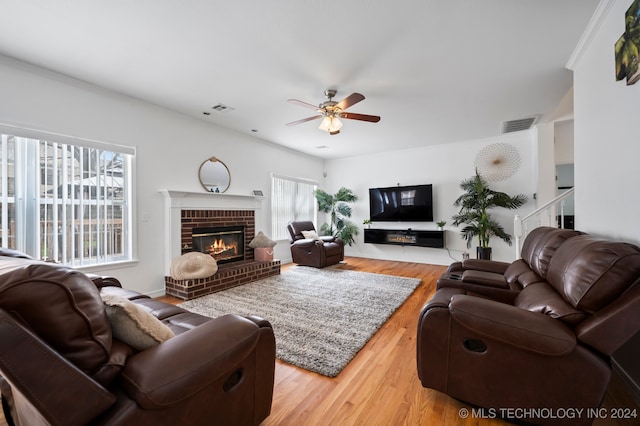 living room with ceiling fan, wood-type flooring, and a brick fireplace