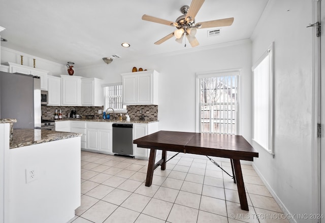 kitchen featuring dark stone countertops, white cabinetry, crown molding, and appliances with stainless steel finishes