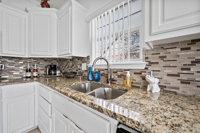 kitchen with backsplash, stone countertops, white cabinetry, and sink