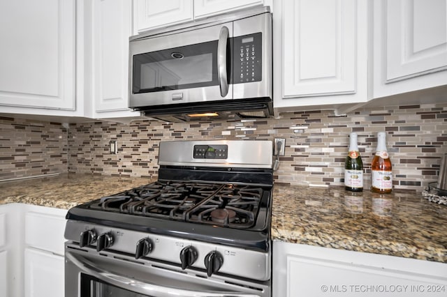 kitchen with dark stone counters, decorative backsplash, white cabinetry, and stainless steel appliances