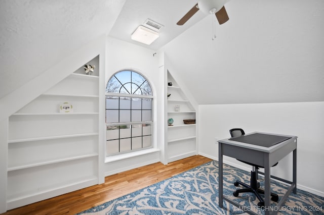 office with built in shelves, ceiling fan, wood-type flooring, a textured ceiling, and vaulted ceiling