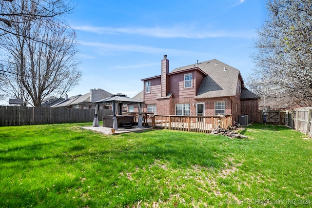 rear view of property with a gazebo, cooling unit, a yard, and a hot tub