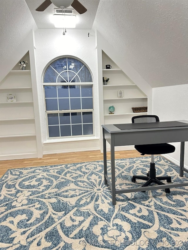 home office with hardwood / wood-style floors, vaulted ceiling, a textured ceiling, and built in features