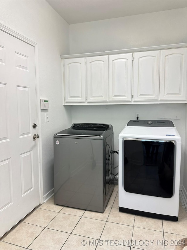 washroom with cabinets, separate washer and dryer, and light tile patterned floors